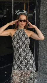 Vestido midi de encaje floral color beige sobre base negra, con cuello halter y falda con vuelo.