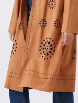 Chaqueta larga color marrón, de símil gamuza calada con diseño de flores y puntos. Tiene silueta abierta y mangas largas de corte recto.