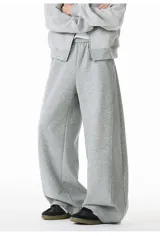 Pantalón de jogging gris de algodón, corte ancho (baggy) y tiro alto, con costura central vertical que recorre la pierna.