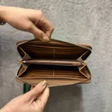 Billetera de cuero rústico color negro con detalles metalizados en azul, cierre metálico, y múltiples compartimentos para tarjetas.