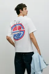 Remera blanca de algodón con cuello redondo y estampado pequeño en el pecho con el texto "Peanuts Racing Team" en color azul.