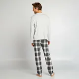 Pijama de dos piezas, compuesto por camiseta de manga larga gris y pantalón de cuadros en blanco y negro.