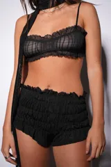 Conjunto de lencería negro de encaje, compuesto por un corpiño tipo bralette y un short con volados.
