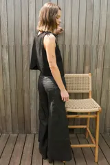 Chaleco negro con cuello redondo y espalda irregular. Detalle de plumas en los hombros.