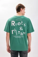 Remera verde con estampa frontal de la marca Roots en color blanco. Corte oversize y mangas cortas.