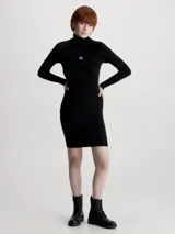 Vestido corto negro de punto acanalado, con cuello alto y mangas largas. Presenta logo de Calvin Klein bordado en el pecho.