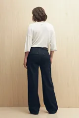 Pantalón de jean azul oscuro, de corte recto y tiro alto, con costuras a la vista.