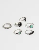 Set de seis anillos plateados con detalles en bajo relieve y apliques símil piedra en color negro y turquesa.