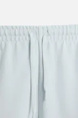 Bermuda azul de corte relaxed fit, confeccionada en tejido interlock de algodón con cintura elástica ajustable con cordón, bolsillos laterales y bolsillo trasero de plastrón.