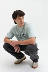 Remera celeste de manga corta con cuello redondo y estampado con la frase "Out of Office All Chasing Dream" en color negro.