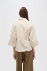 Chaqueta color beige de viscosa con botones, cuello camisero y cordón ajustable en la cintura.
