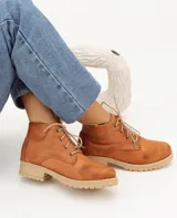 Bota acordonada color marrón claro de cuero, con suela de goma color beige y cordones finos blancos.