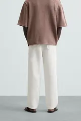 Pantalón color arena de corte recto, confeccionado en tejido de algodón y lino. Cuenta con cintura elástica ajustable con cordón, bolsillos delanteros y traseros de parche.