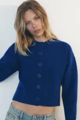 Chaqueta de punto color marrón con aberturas laterales y cierre frontal con botones.