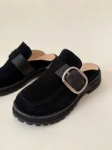 Zueco negro de cuero con hebilla metálica plateada y suela track.