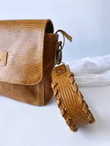 Bandolera color camel de cuero con forro de tela, correa corta con tientos y bolsillo interno.