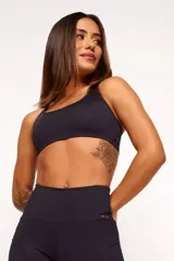 Top deportivo negro con diseño nadador, entrada para almohadillas removibles, bolsillo trasero y detalle reflectivo.