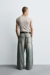 Pantalón de jeans de algodón, corte baggy fit, tiro medio, con efecto lavado en tonos grises y verdes. Presenta cinco bolsillos y cierre frontal con cremallera y botón.