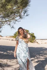 Vestido midi blanco con estampado floral en tonos verdes, escote en V, mangas cortas abullonadas y corte evasé.