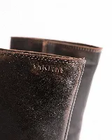 Bota de cuero color marrón oscuro, de caña media, con hebilla y tachas decorativas.