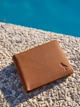 Billetera de cuero color marrón claro, con diseño minimalista y cierre a presión.