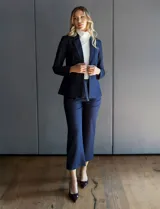 Blazer de tencel color azul marino con cuello de solapa y cierre frontal de un solo botón. Presenta bolsillos delanteros simulados con detalle de vivo trenzado y un diseño estructurado de calce entallado.