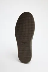 Zapatillas deportivas marrones con detalles en color crema y suela plana.