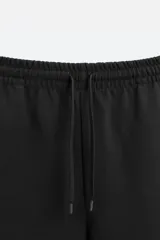 Bermuda negra relaxed fit confeccionada en tejido interlock de algodón con elasticidad. Cintura elástica ajustable con cordón. Bolsillos laterales y detalle de bolsillo trasero de plastrón.