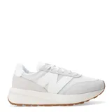 Championes urbanos New Balance 370, color blanco con detalles en gris, confeccionados en gamuza y malla, con logo "N" característico en los laterales y suela de goma color caramelo.