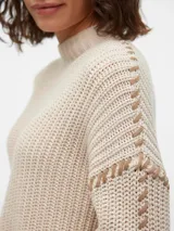 Sweater de punto color crema con cuello alto, mangas largas y hombros caídos.