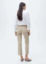 Pantalón de jean color beige, tiro medio, corte flare, con bolsillos de parche delanteros y ruedo desflecado.