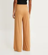 Pantalón recto color ocre, de tejido rib con textura acanalada y pliegues en la cintura.