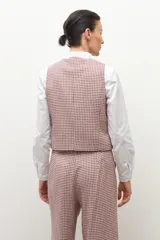 Chaleco de vestir sin mangas, color beige con estampado de cuadros pequeños en tonos rojizos y marrones. Tiene cuello solapa y cierre frontal con botones oscuros.