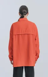 Camisa naranja de manga larga, estilo técnica con múltiples bolsillos delanteros y un bolsillo en la parte inferior de espalda, botones en cartera y mangas, calce oversize.