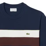 Remera Lacoste azul marino con franjas horizontales blancas y marrones en el pecho y logo de la marca bordado en verde.