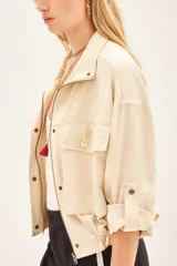 Campera marrón de lino con cierre frontal y bolsillos con solapa. Tiene mangas largas con presilla interna para arremangar.