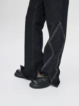 Pantalón de jean azul de tiro alto y corte oxford con apliques metálicos en bolsillos y laterales.