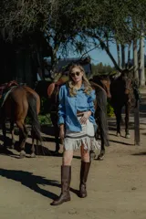 Minifalda marrón de cuero ovino con flecos y cierre frontal.