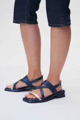 Sandalias bajas de cuero color marrón con tiras cruzadas y detalle de tira delgada color rosa.