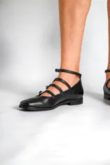 Chatas de cuero negro con punta fina, cuatro tiras horizontales con hebilla y pulsera al tobillo.