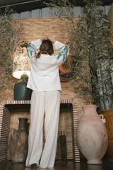 Pantalón de lino color crudo con corte amplio y estampado de palmeras en la parte inferior de las piernas.