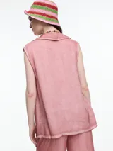 Camisa gris sin mangas confeccionada en viscosa teñida en frío, con efecto gastado. Tiene cuello clásico, cartera oculta y ruedo irregular más largo en los laterales.