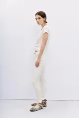 Pantalón jean blanco de tiro alto y calce skinny, con proceso de coating de acabado símil cuero. Pierna al cuerpo hasta el tobillo.