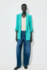 Blazer marrón con cuello solapa y hombreras. Manga tres cuartos con trabilla y botón dorado. Bolsillos delanteros con solapa.