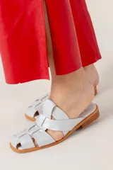 Zueco marrón de cuero vacuno con diseño de tiras entrecruzadas y suela plana.