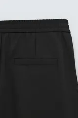 Pantalón negro de corte recto, con cintura elástica, bolsillos laterales y trasero.
