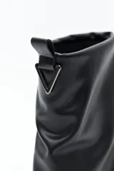 Bota de caña baja negra de poliuretano con acabado liso y efecto fruncido. Presenta puntera redondeada, base baja y cierre trasero con tirador metálico.