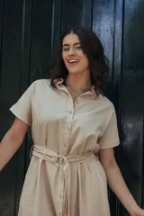 Vestido color beige con botones frontales y cinturón para un ajuste personalizado.