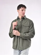 Campera verde militar con cuello clásico, cierre frontal con botones, dos bolsillos con solapa en el pecho y corte recto.