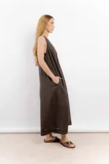 Vestido largo confeccionado en lino de color beige, con escote en V, diseño sin mangas y silueta holgada de caída fluida.